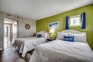 A hotel room with two beds, a window with curtains, a wall-mounted ship's wheel, and a framed picture. - ☀️Oceanfront 1BR | Balcony | Pools & Lazy River | Atlantica Resort 1103☀️ (Myrtle Beach)