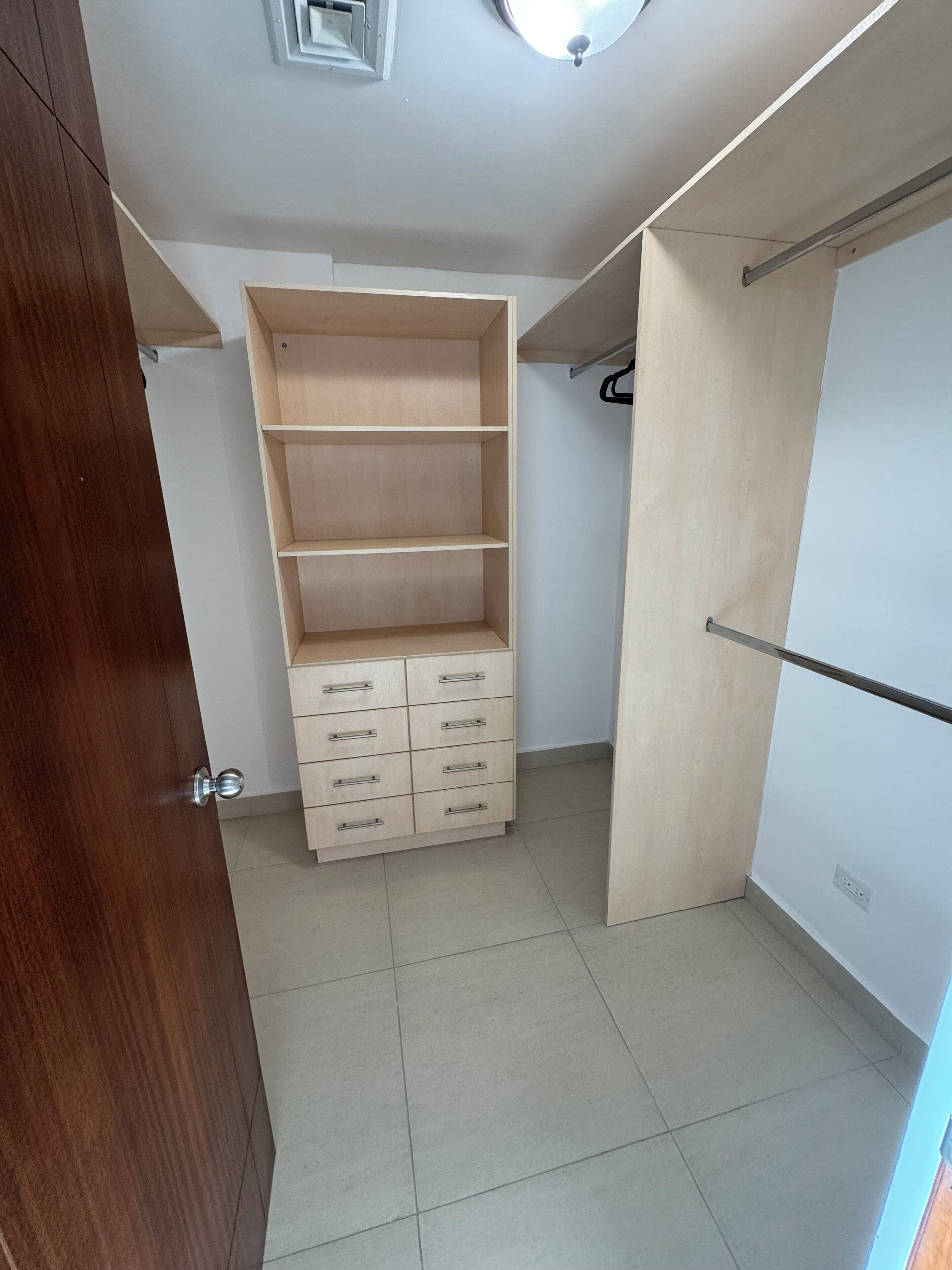 Un dressing avec des étagères ouvertes, une tringle et une armoire.