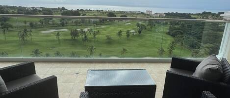 Un balcón con mobiliario de mimbre y vista a un campo de golf.
