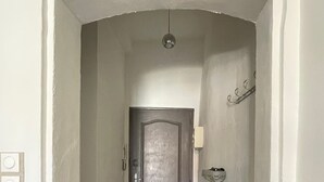En hall med en dörr, en liten bänk och en väggmonterad lampa.