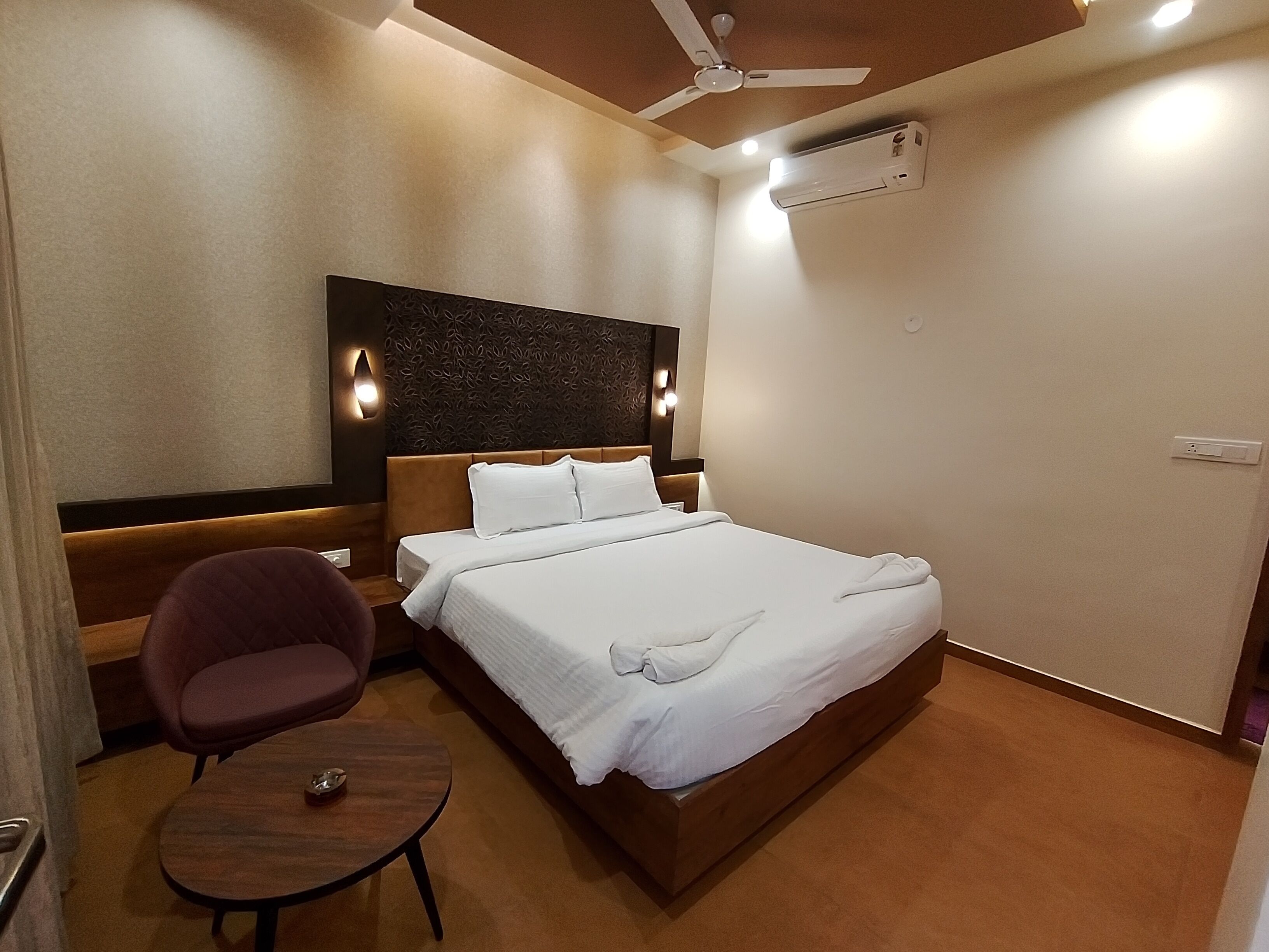 Une chambre d’hôtel équipée d’un lit, d’une chaise, d’une petite table, d’un ventilateur de plafond et d’un appareil de climatisation.