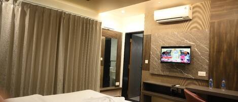 Ein Hotelzimmer mit Bett, Schreibtisch mit Stuhl, Fernseher an der Wand und Klimaanlage.