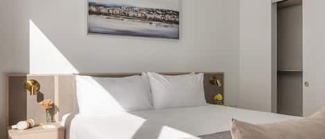 A hotel room with a bed, a nightstand, a lamp, and a painting on the wall.
