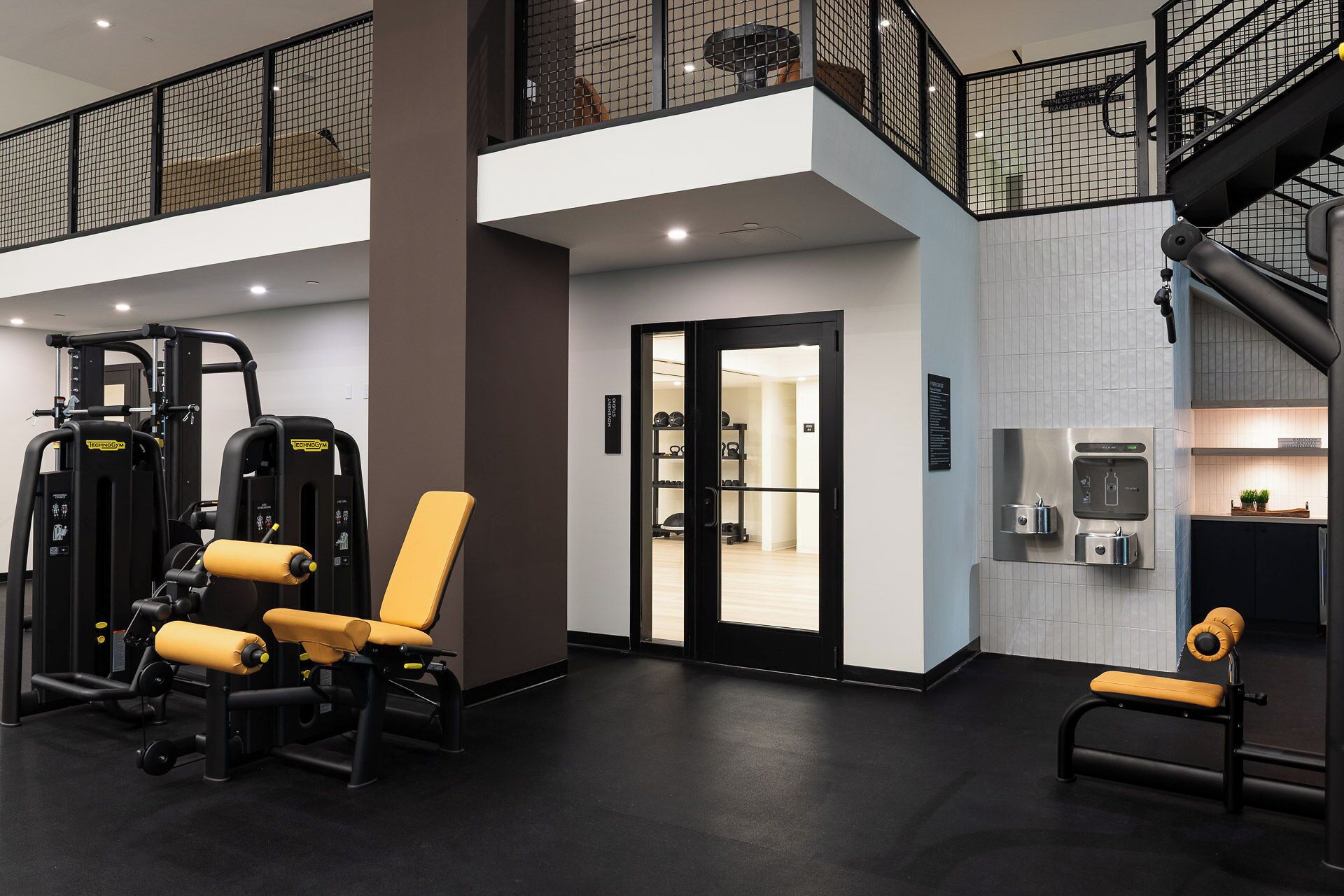 A gym with exercise equipment, a bench, and a water dispenser.