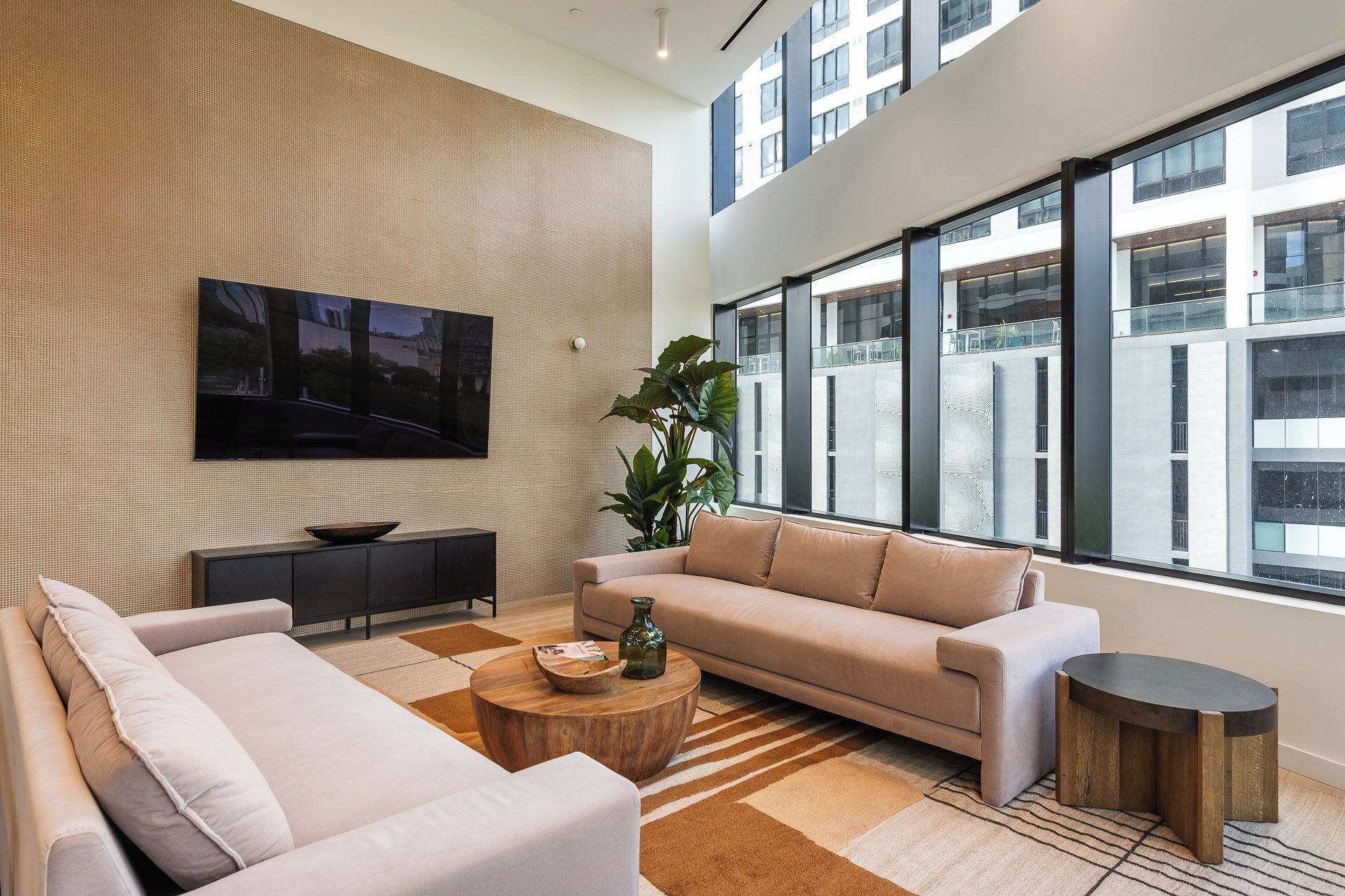 A modern living room with a large window, a flat-screen TV, a sofa, a coffee table, and a side table.