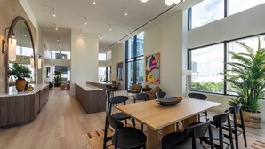 A spacious modern kitchen with a central island, large windows, and a dining area with a wooden table and black chairs. - District 225 by Nomada (Miami)