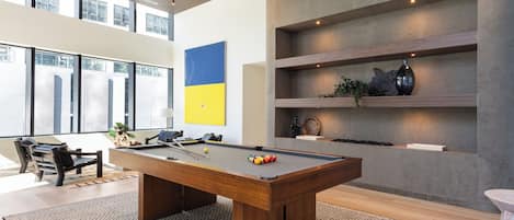 A modern indoor pool table with a wooden finish, surrounded by a patterned rug.