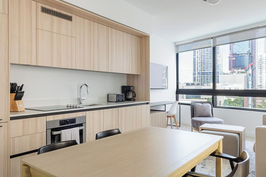 Une cuisine moderne avec des meubles en bois, un évier en acier inoxydable et une grande fenêtre donnant sur la ville.