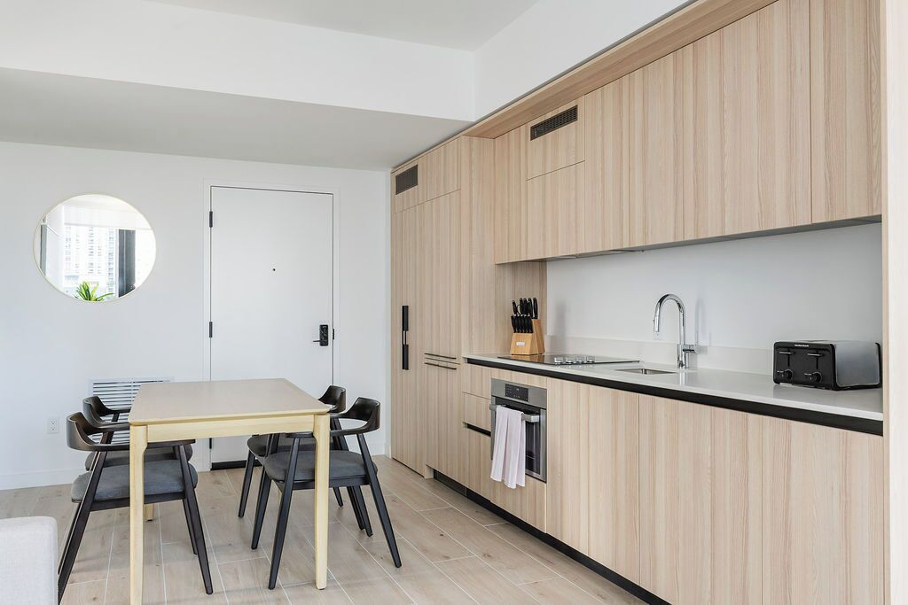 Una cocina moderna con armarios de madera, horno empotrado, lavabo y un espejo redondo en la pared.