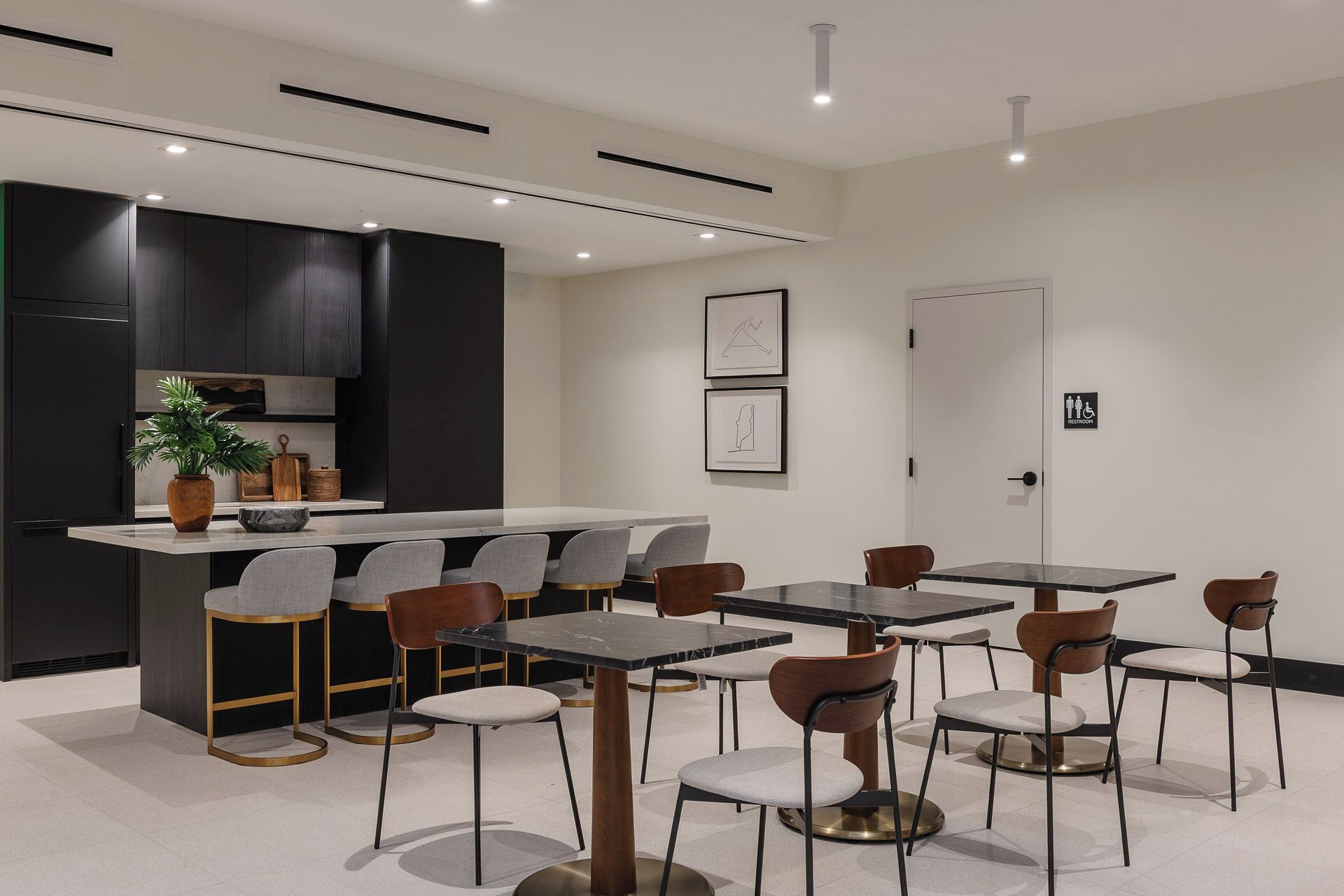 Una cucina moderna con mobili scuri, un'isola centrale e un'area con tavoli e sedie.