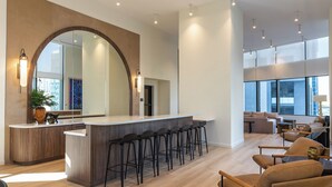 A modern kitchen with a bar area, wooden flooring, and a large mirror. - District 225 by Nomada (Miami)