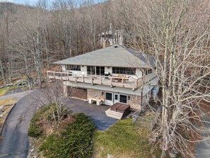A two-story building with a balcony, stone foundation, and a paved driveway. - Seven Devils Sky Haven: Hot Tub, Tubing, and Mountain Views (Seven Devils)