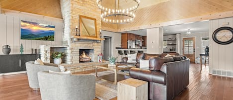 Amplia sala de estar con chimenea, sofá de cuero y comedor.
