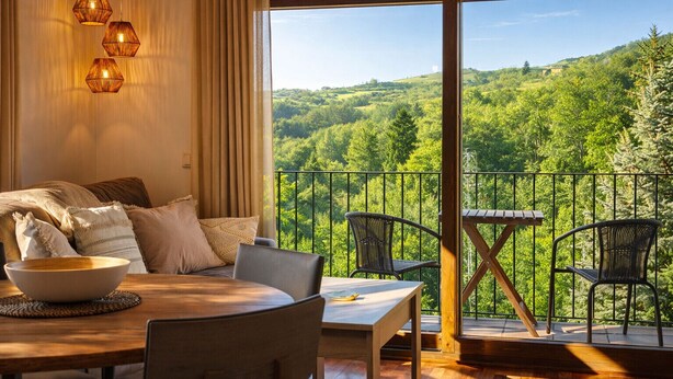 A cozy room with a dining area and a balcony overlooking a forested landscape. - Vall de Muntanyes - Costabona (Molló)
