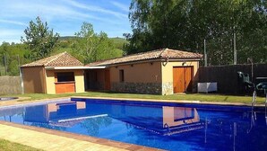 A swimming pool with two adjacent buildings, one with a door and the other with a window. - Vall de Muntanyes - Costabona (Molló)