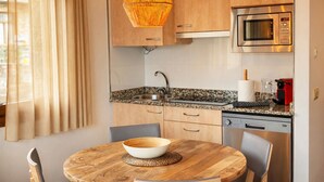 Une cuisine compacte dotée de meubles en bois, d’un plan de travail en granit, d’un four à micro-ondes encastré et d’une machine à café.