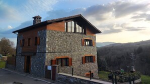 Un bâtiment en pierre de deux étages, doté d’un toit en pente et de volets en bois aux fenêtres.