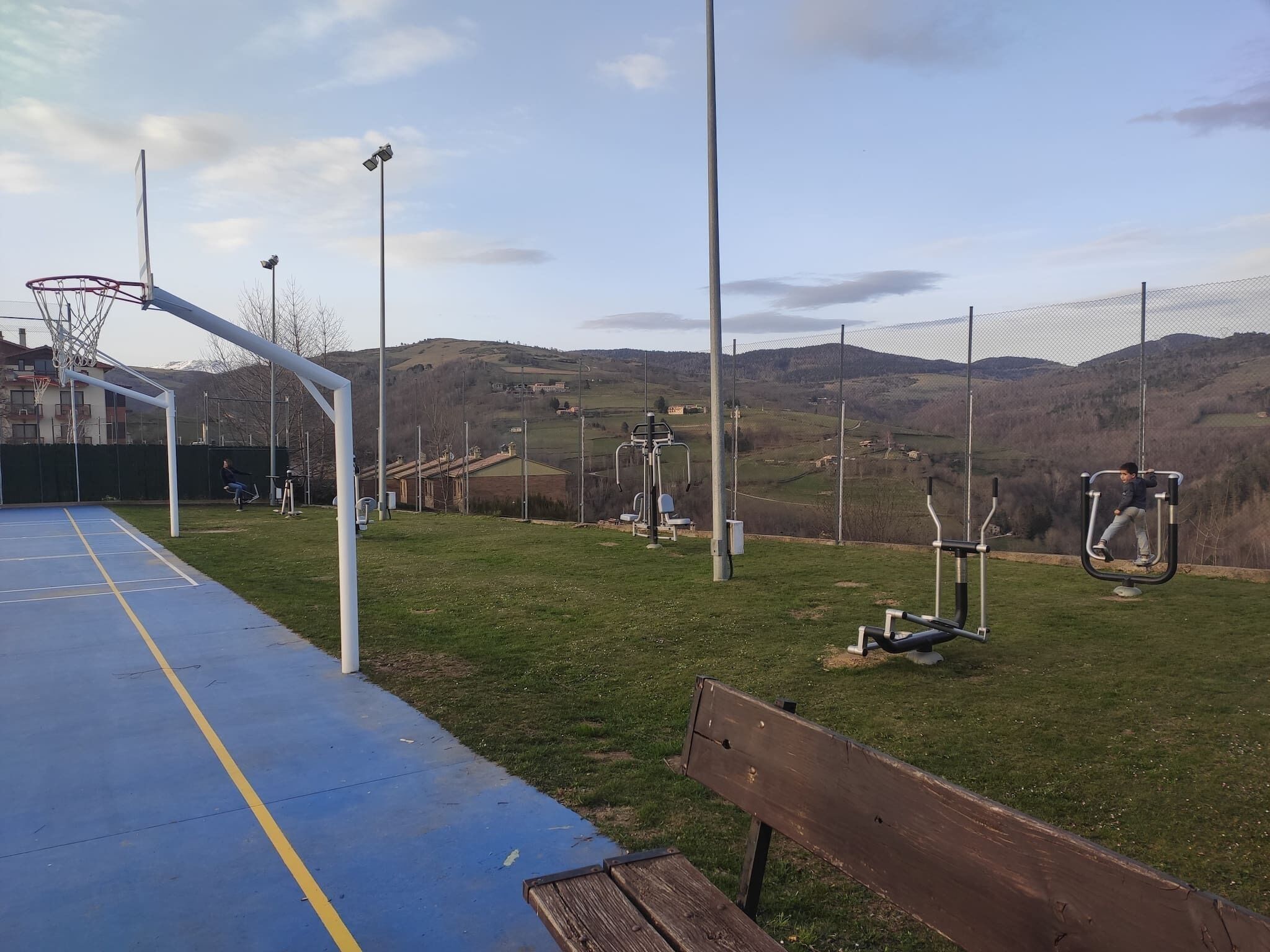 Ein Basketballfeld mit Korb, Trainingsgeräten und einer Bank.