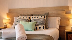 Un lit bien fait, avec des coussins à motifs et une serviette pliée.
