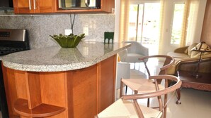 Una cocina con encimeras de granito, armarios de madera, estufa de acero inoxidable y un tazón decorativo verde.
