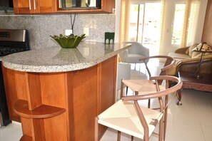 A kitchen with granite countertops, wooden cabinets, a stainless steel stove, and a green decorative bowl. - Comfortable and spacious apartment in Torre Alta (Puerto Plata)