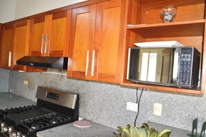 A kitchen with wooden cabinets, a stainless steel stove, and a microwave. - Comfortable and spacious apartment in Torre Alta (Puerto Plata)