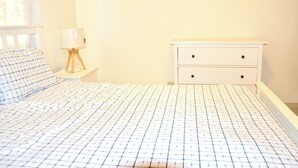 Un dormitorio con cama, mesita de noche, lámpara y cómoda.