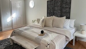 Ein Schlafzimmer mit Bett, Nachttischen, einer Bank und dekorativen Wandverkleidungen.