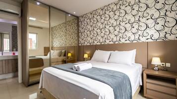 A modern hotel room with a large bed, bedside lamps, a mirror, and a patterned wall.