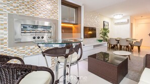 A modern kitchen with a built-in oven and microwave, a glass-top dining table, wicker furniture, and a dining area with chairs. - Aprts in a Condomin. 500m fr/ the Balneario Camboriu Ferris Wheel - Iors (Balneário Camboriú)