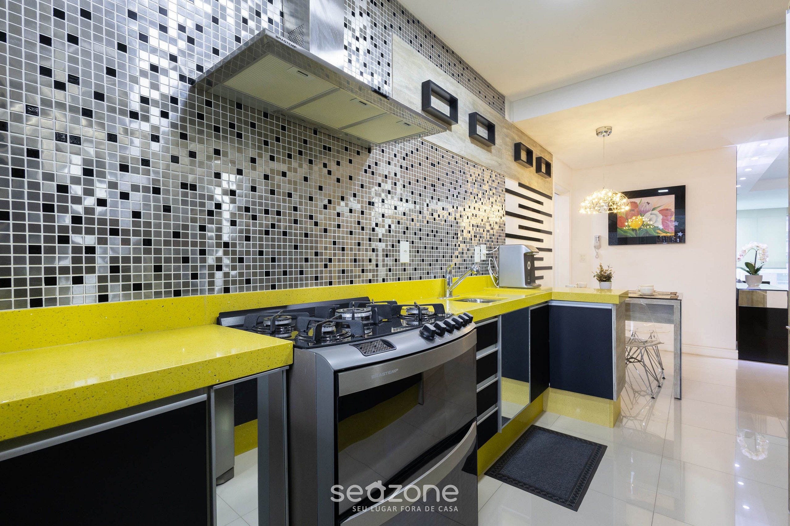 A modern kitchen with a yellow countertop, stainless steel appliances, and a mosaic backsplash.