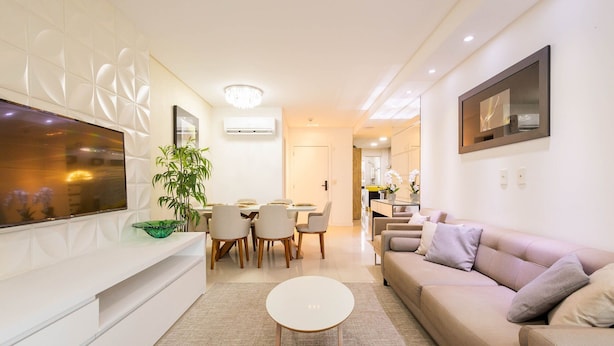 A modern living room with a sofa, a dining table with chairs, a TV, and a plant. - Aprts in a Condomin. 500m fr/ the Balneario Camboriu Ferris Wheel - Iors (Balneário Camboriú)