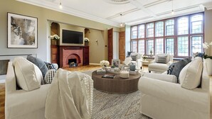 Un salón amplio con chimenea, ventanas grandes y una mesa de centro redonda.