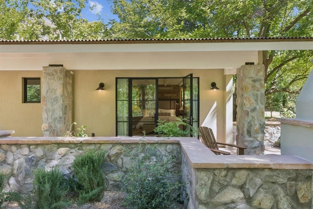 Una casa moderna con fachada de piedra, puerta de cristal y un patio con una silla.