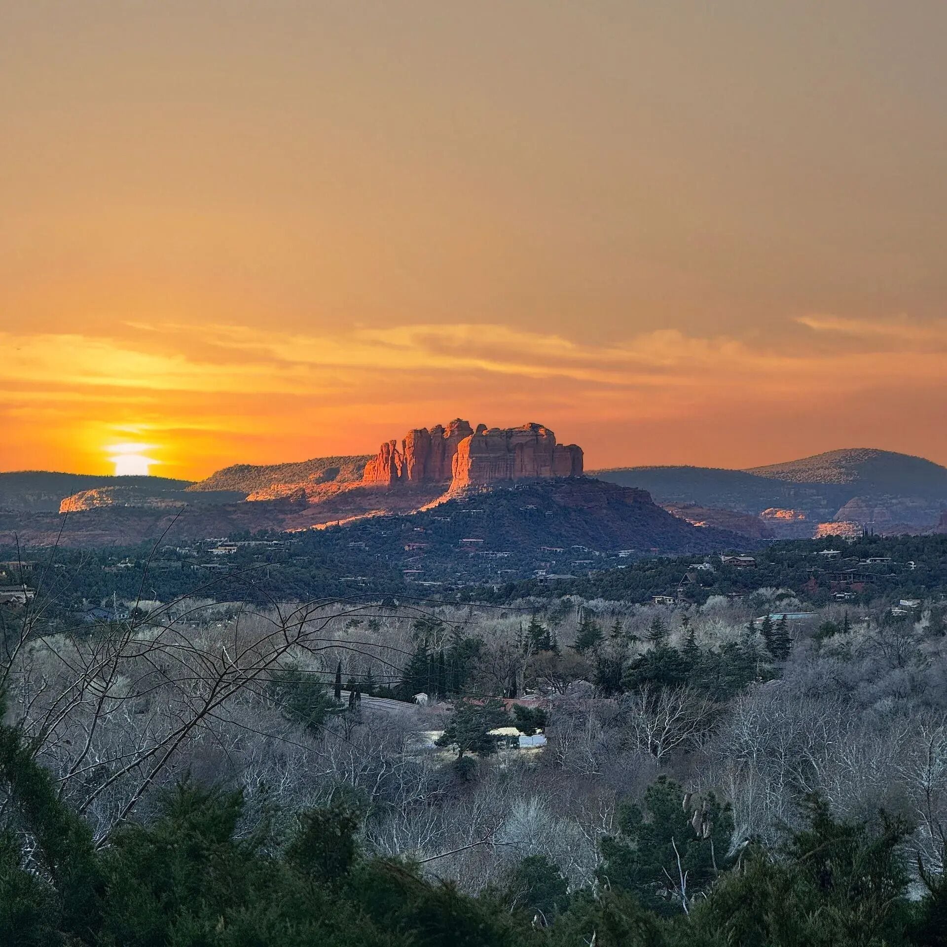A mountainous landscape with a prominent rock formation at sunset.