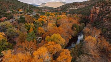 A canyon with autumn foliage, a river, and a small cabin.