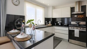 Eine moderne Küche mit Kochinsel, schwarzen Arbeitsplatten, Edelstahlgeräten und einem großen Fenster für natürliches Licht.