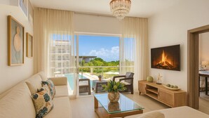 A spacious living room with a sofa, coffee table, and a TV mounted on the wall. - Spacious and Elegant 2BR Condo, King size Bed, Full AC, Pool, Steps to Hard Rock (Punta Cana)