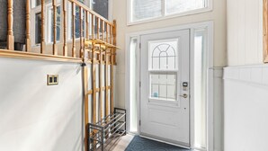 Una scala con balaustre in legno, una porta bianca con un vetro e un tappetino blu.