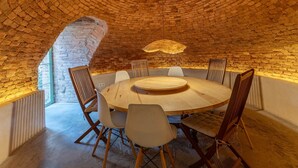 A round wooden table with chairs in a room with a brick ceiling and a sloped ceiling. - Casona Única in Gredos Valley - Private Pool and Shared Patio in Candeleda (Candeleda)