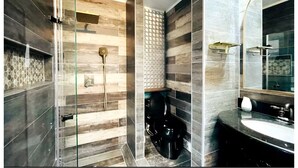 Un baño moderno con cabina de ducha de vidrio, inodoro y lavamanos con un espejo grande.