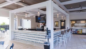 Ett modernt utomhusområde med bar, sittplatser och en tv-skärm.