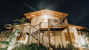 Una struttura in legno a più livelli con una scala, circondata da piante tropicali.