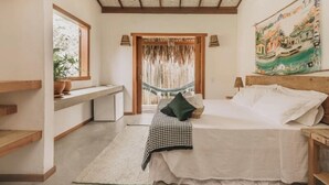 Una camera da letto con un letto, una scrivania, un'amaca e un quadro appeso al muro.