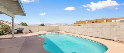 A swimming pool with a curved design, surrounded by a concrete deck and a brick wall.