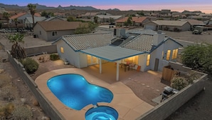 Una casa con piscina, un patio cubierto y vistas del barrio circundante.