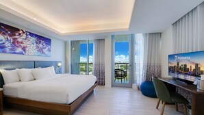 A modern hotel room with a large bed, a desk, a television, and a balcony with a city view. - Spacious Modern Studio • Pool & Balcony • Circ Hotel (Hollywood)