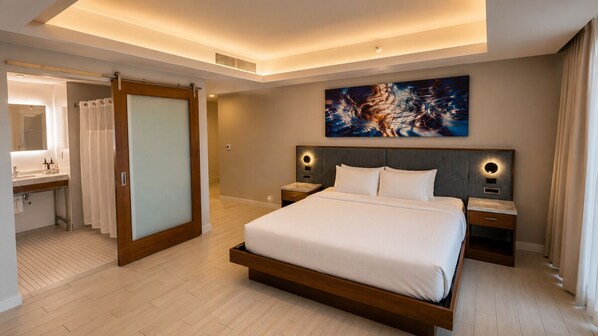 A modern hotel room with a large bed, bedside tables, a nightstand, a painting on the wall, and a bathroom with a shower curtain. - Spacious Modern Studio • Pool & Balcony • Circ Hotel (Hollywood)