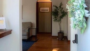 Ein Flur mit Holzboden, einer Couch, einem kleinen Tisch und einem Blumentopf.