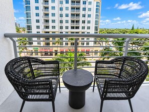 A balcony with two wicker chairs and a round table, overlooking a cityscape with buildings and greenery. - Sunny Studio with Pool & Balcony at Circ Hotel (Hollywood)